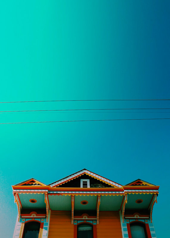 A photograph of a traditional New Orleans home showing the architecture style in the Bywater neighborhood with bright blue sky above. 